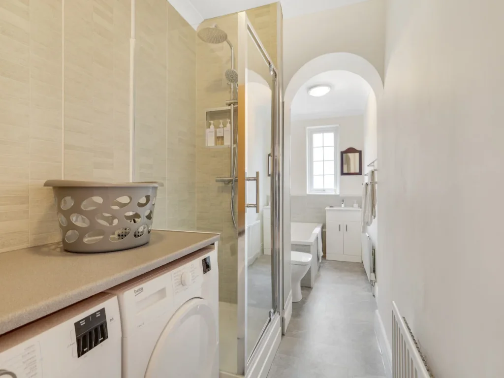 Bathroom and utility area with shower, washing machine and worktop