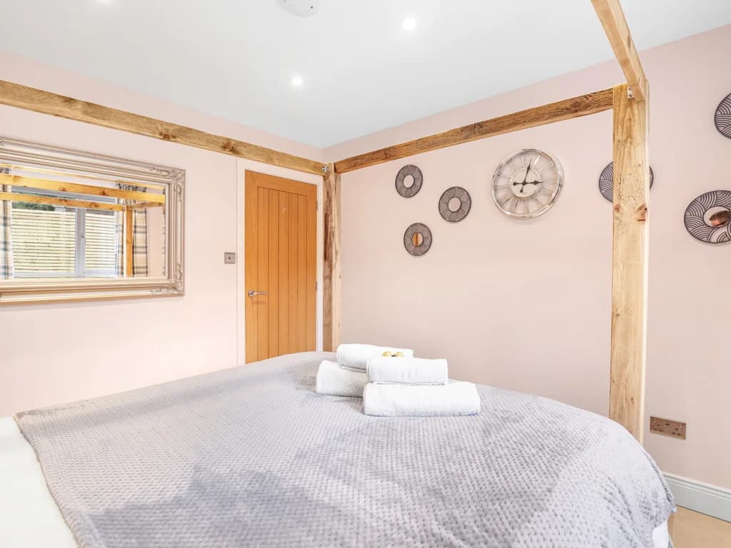 A decorative wall clock and circular mirrors accent the walls of this bedroom, which is furnished with a rustic wooden four-poster bed.