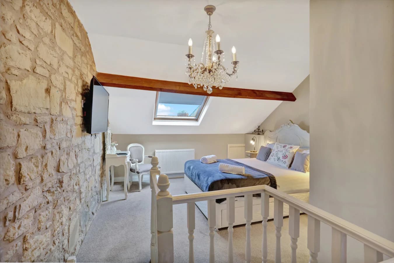 Upper-floor landing with exposed stone wall and seating area beneath beams
