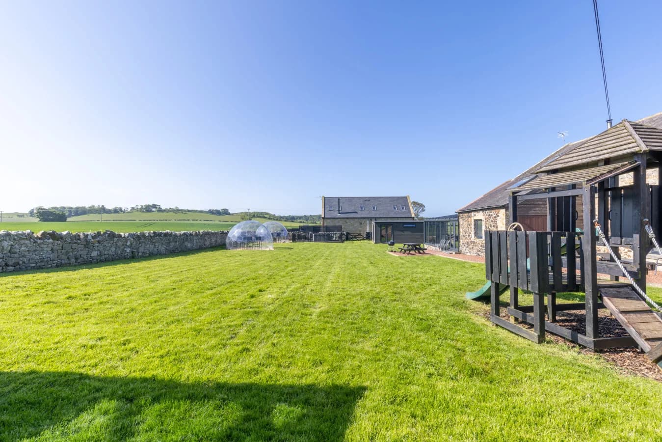 Shared lawn bordered by stone cottages and garden pods