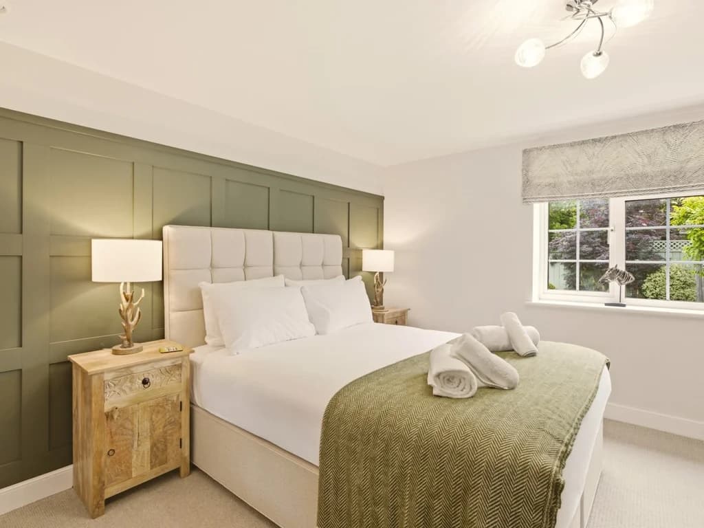 Stylish zip-link king bedroom with feature wall and peaceful garden outlook