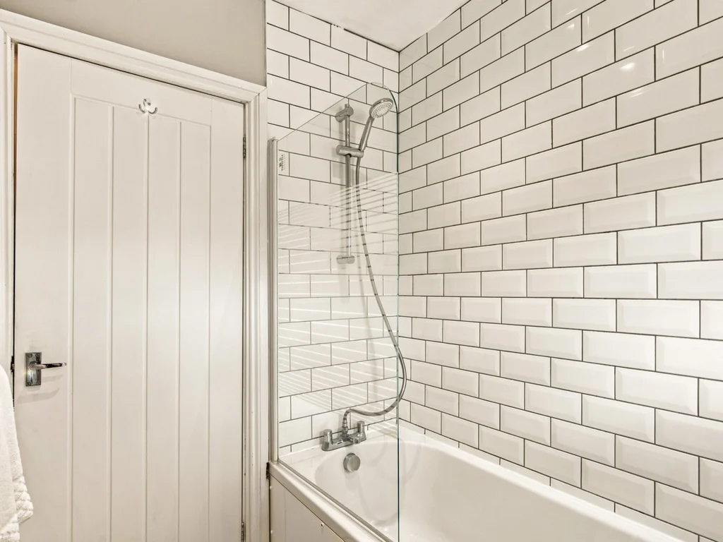 Family bathroom with shower over bath and white subway tile surround.