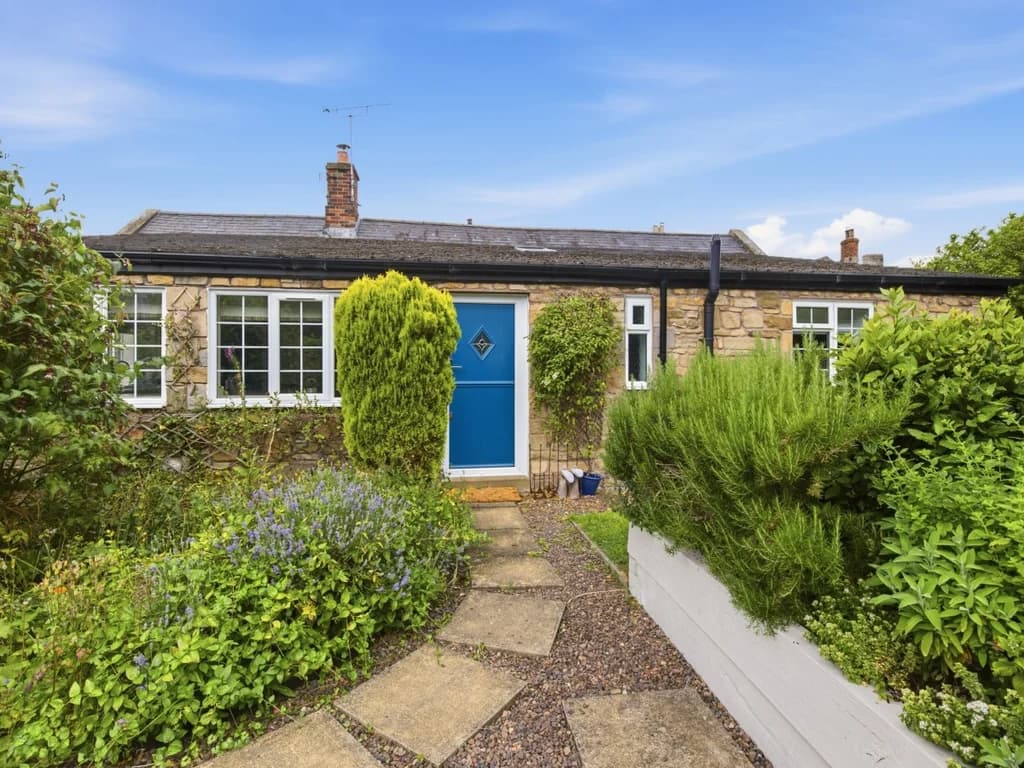 Charming stone cottage with colourful front garden and welcoming blue entrance door