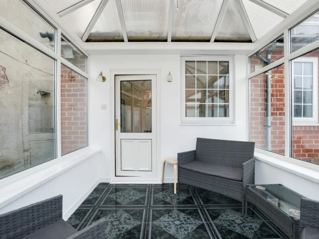 Bright conservatory with comfortable seating and access to the garden
