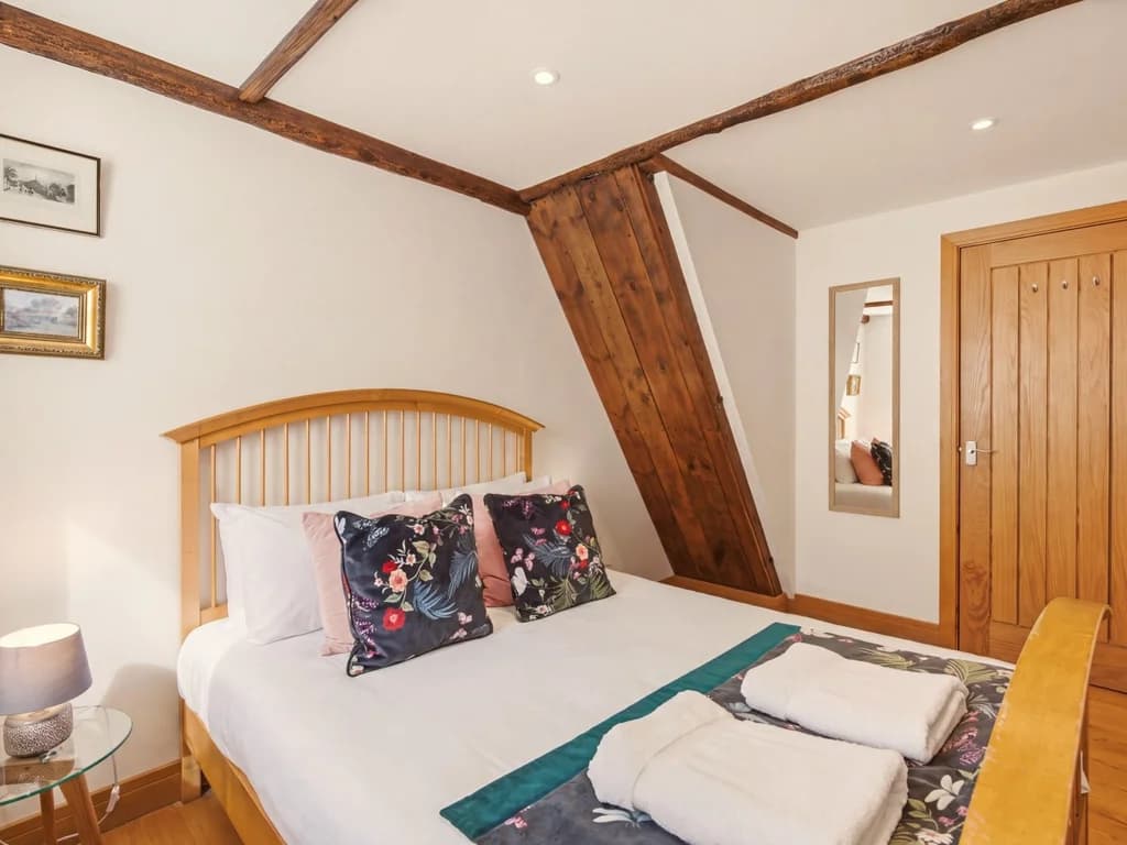 Comfortable bedroom with wooden bed frame and original timber beams