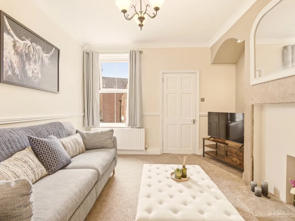 Living room with feature fireplace, grey sofa and Smart TV.