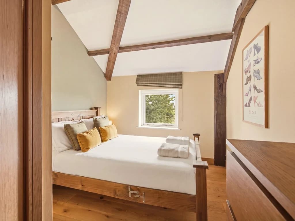 King-size bedroom with timber bed frame and exposed ceiling beams
