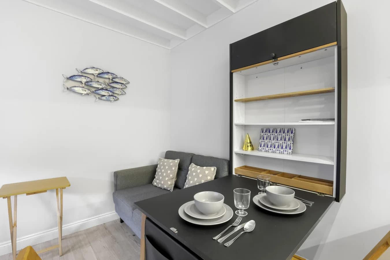 Dining table for two with coastal artwork and open shelving