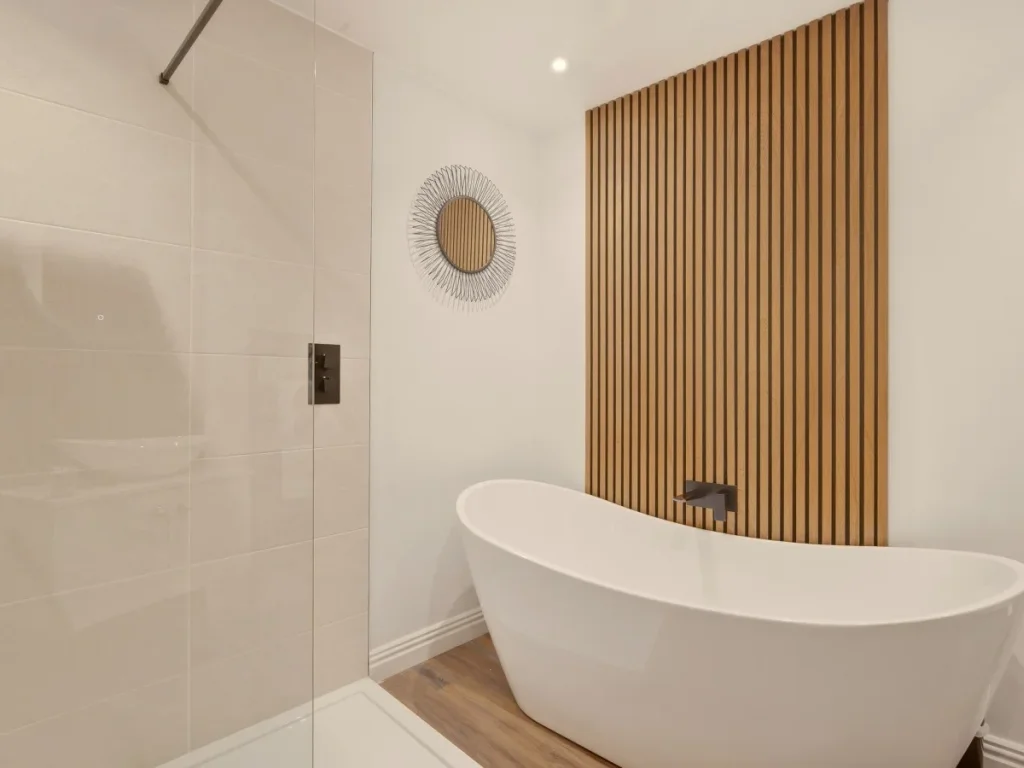 Family bathroom with freestanding bath and vertical wood slat feature wall.