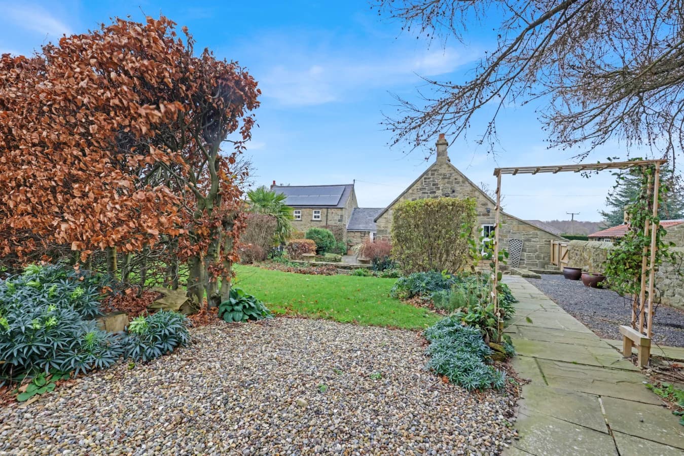 Landscaped grounds with ornamental planting and orchard beyond