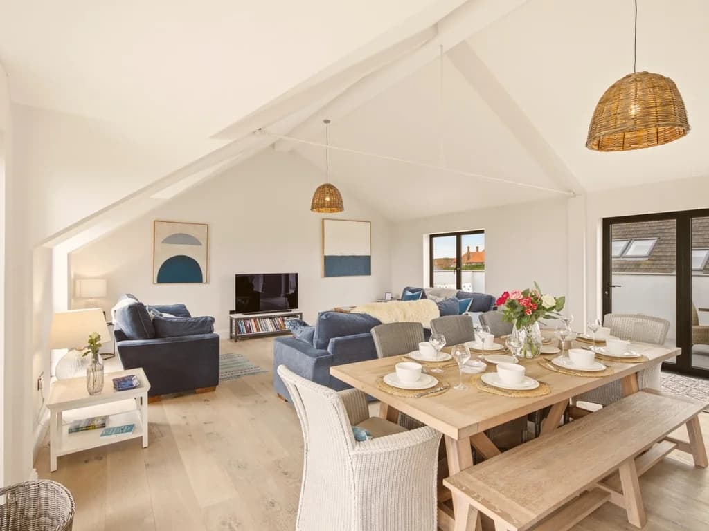 Light-filled living and dining area with vaulted ceilings and balcony access