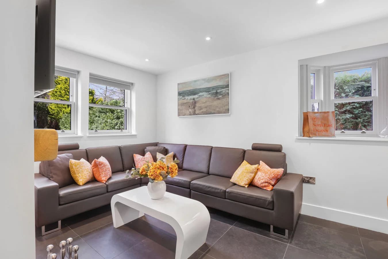 Living area with corner sofa, dual-aspect windows and log burner