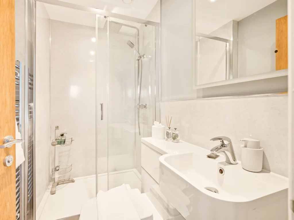 Modern en-suite shower room with glass enclosure, basin and mirrored cabinet
