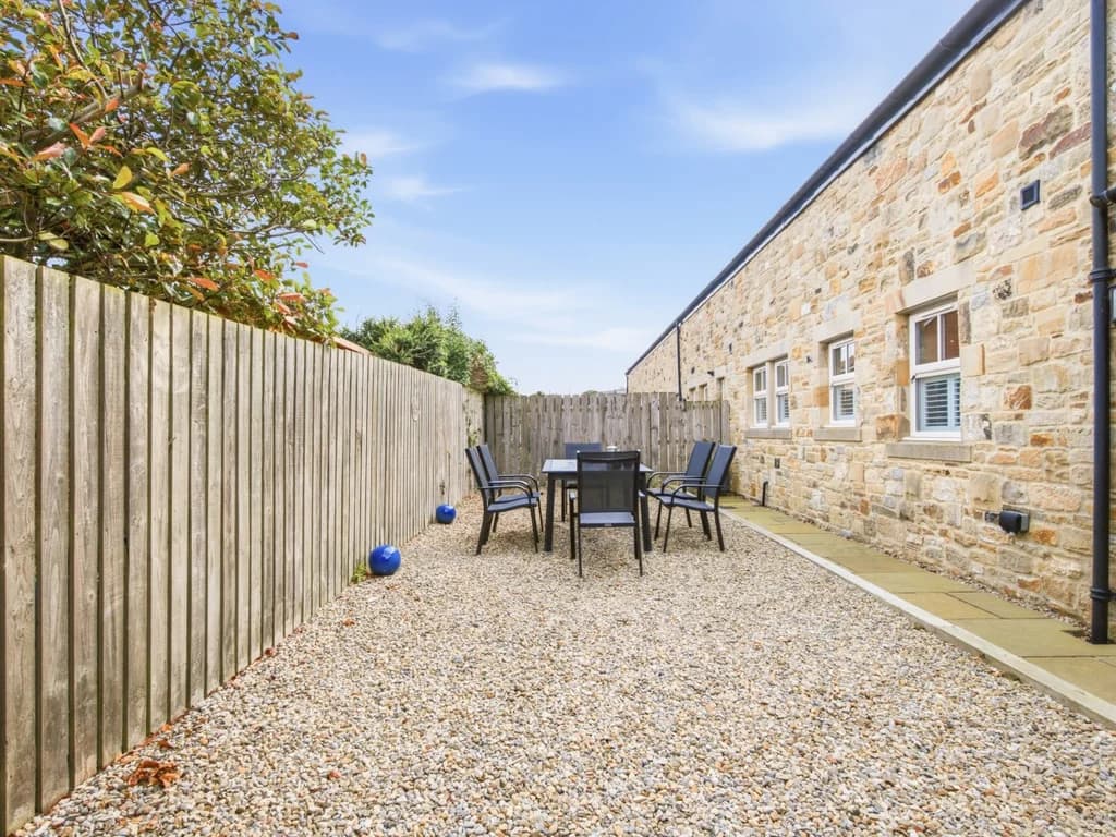 Fully enclosed gravel garden with outdoor dining table and seating