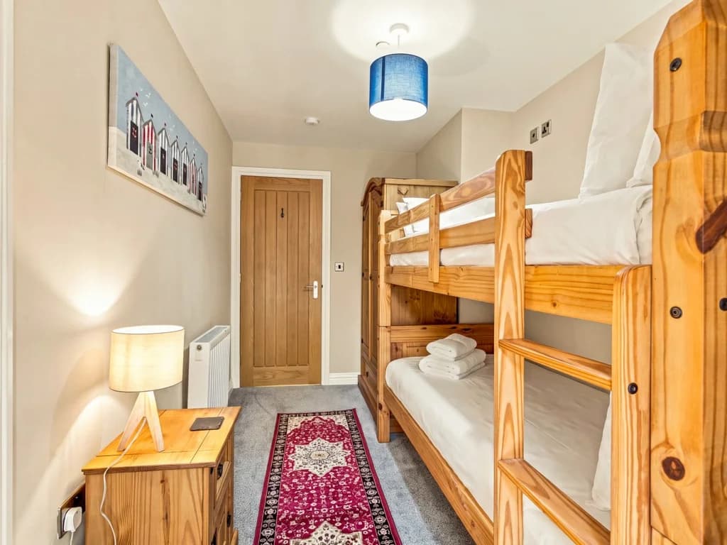 Bunk bedroom with solid wooden bunks and bedside table.