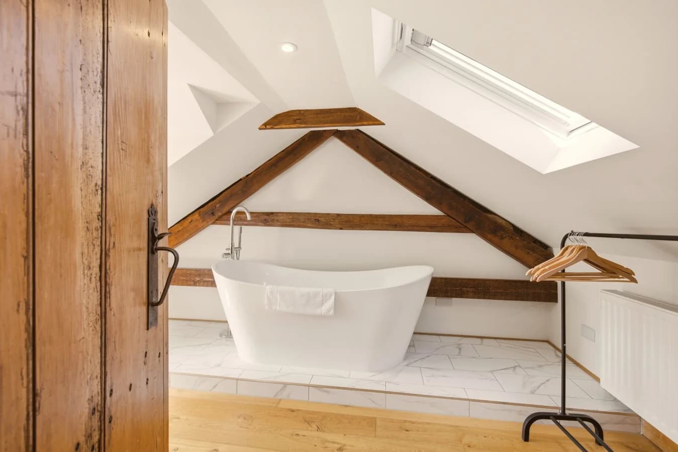 Freestanding bath beneath skylight and original exposed timber beams