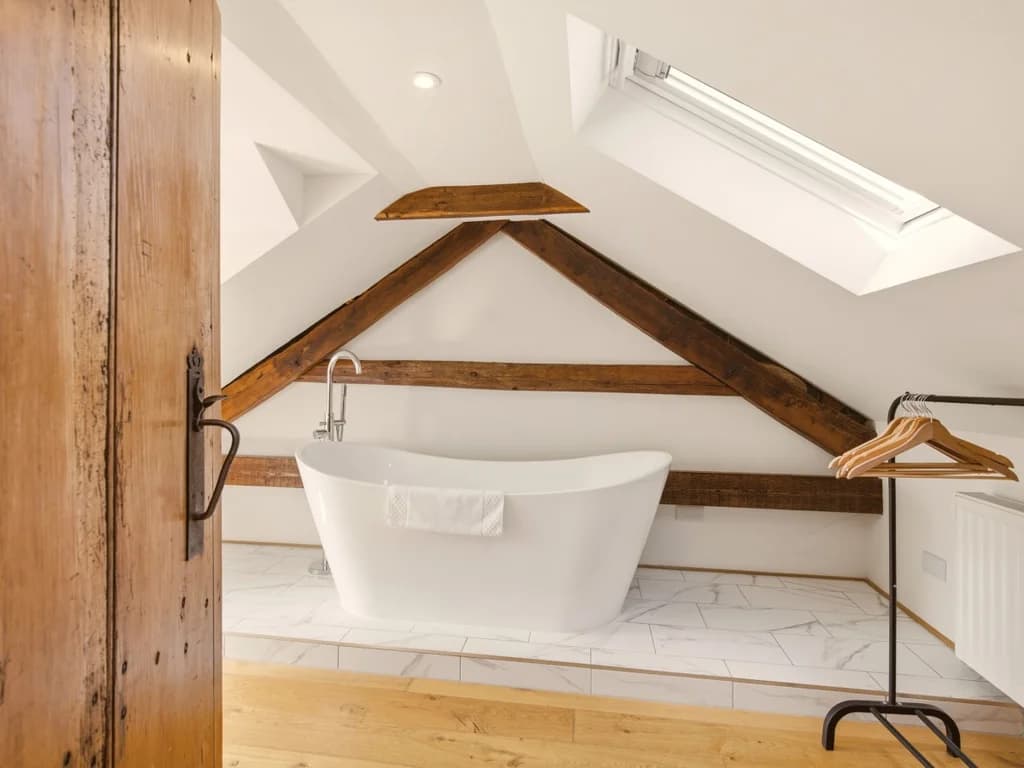 Freestanding bath beneath skylight and original exposed timber beams