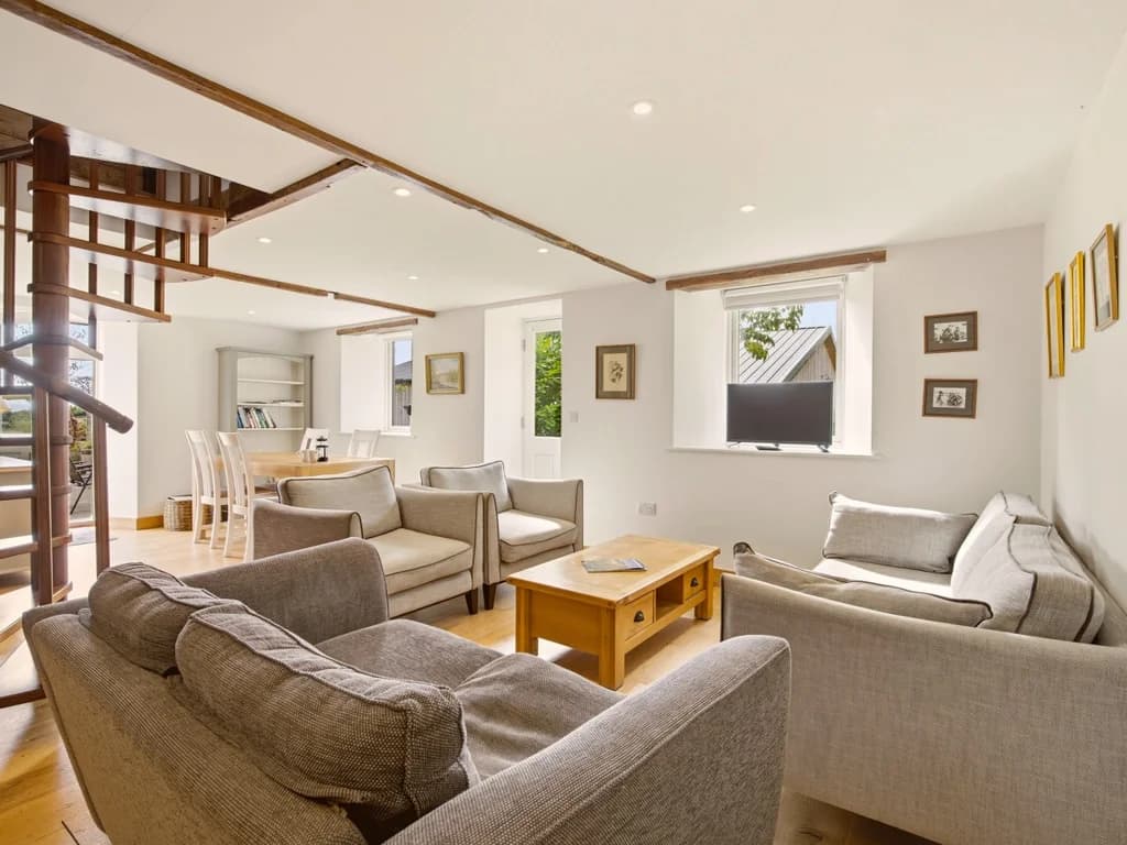 Spacious lounge with sofas, TV and spiral staircase