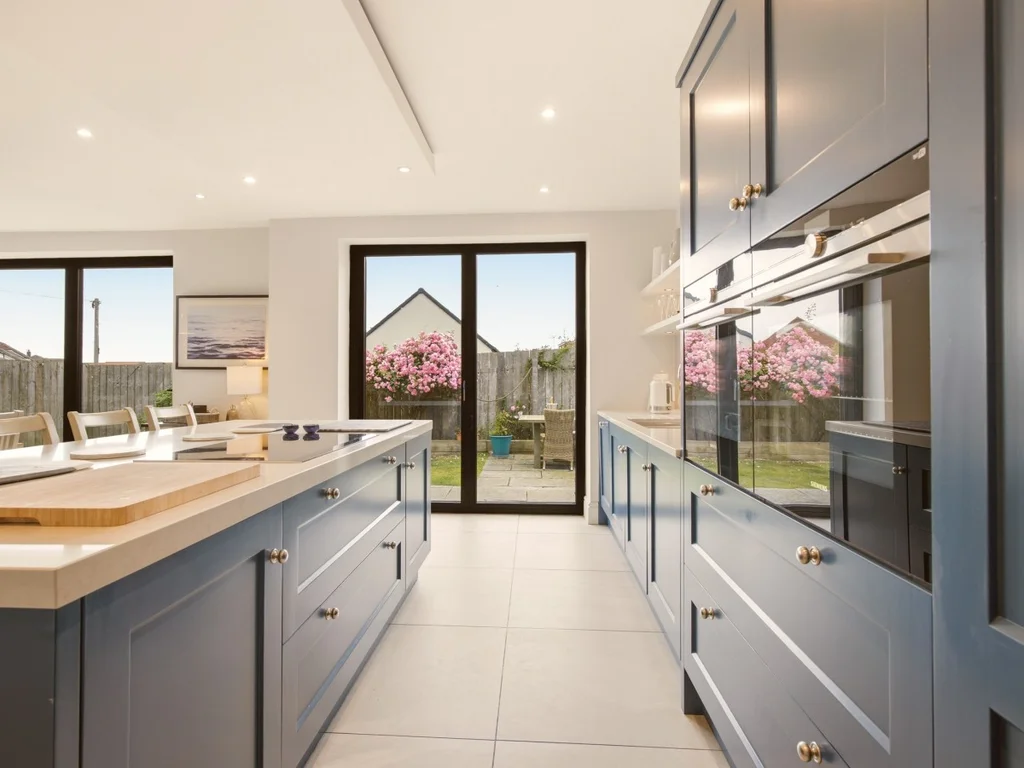 Galley-style kitchen with quartz worktops, integrated appliances and island