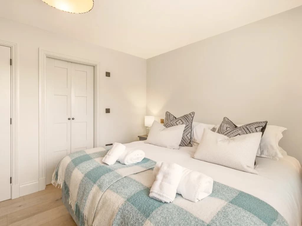Super king bedroom with fitted wardrobe and soft blue checked throw