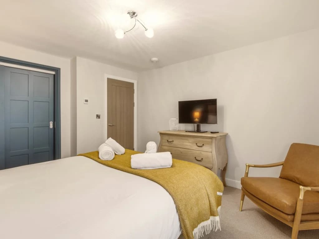 Spacious zip-link king bedroom with Smart TV, armchair and built-in wardrobe