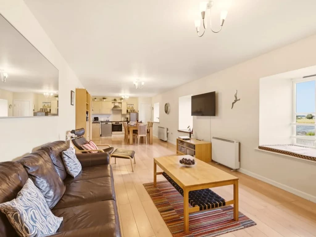 Spacious open-plan living area with leather seating and bay views