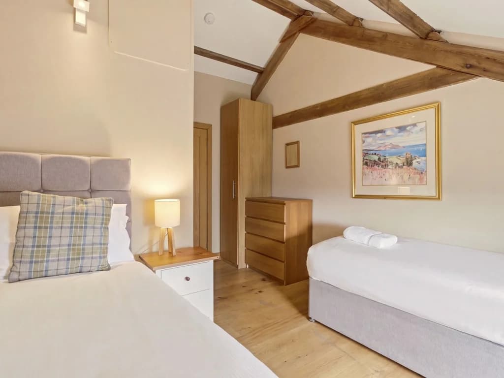 Twin bedroom with exposed beams, timber flooring and storage drawers
