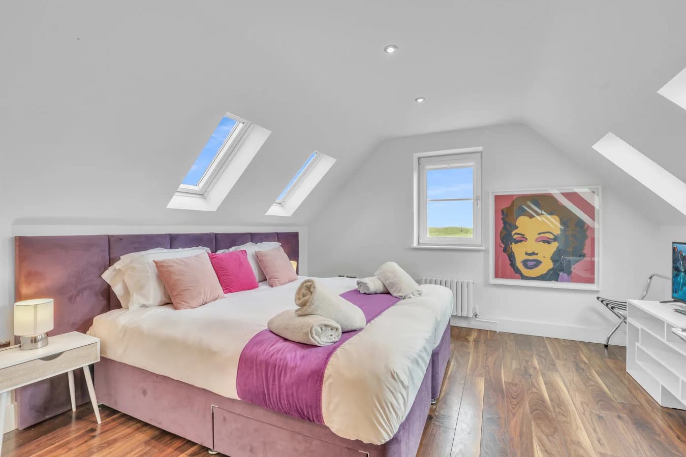Elegant king bedroom with skylights and contemporary artwork