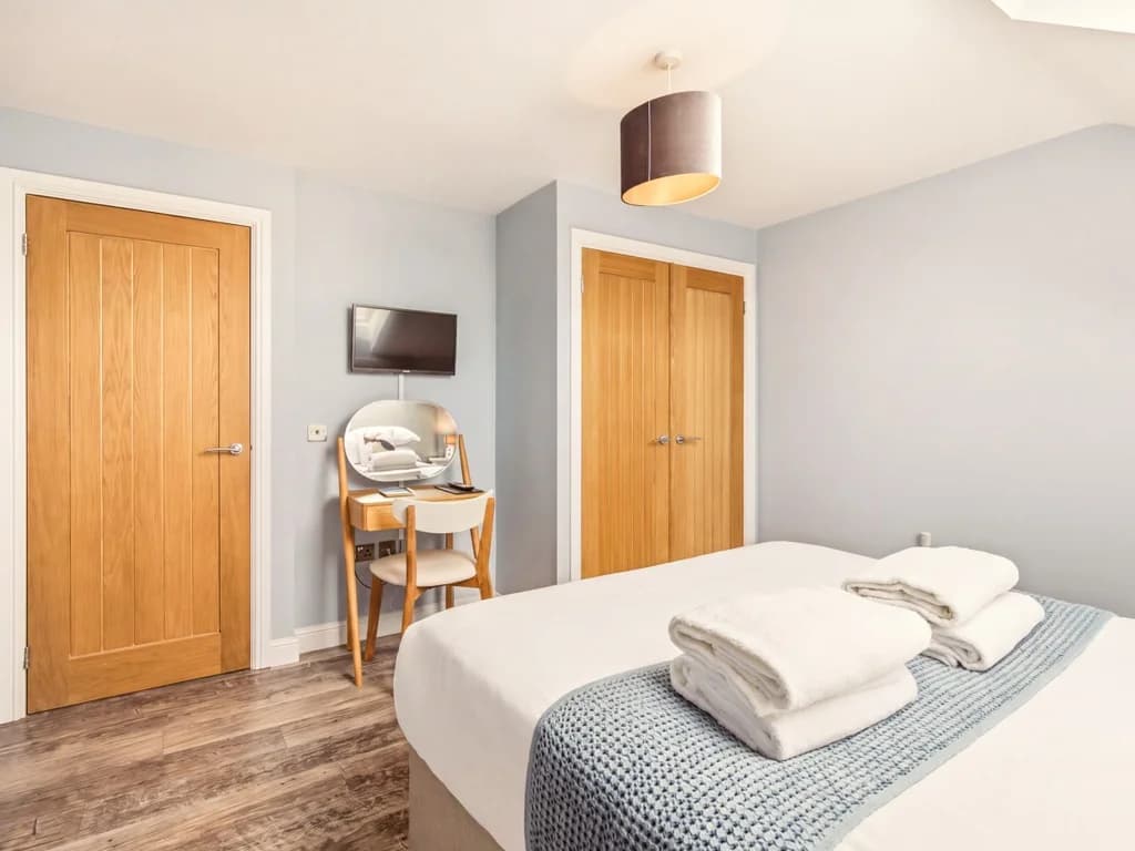 Bright king-size bedroom with dressing table and generous built-in storage