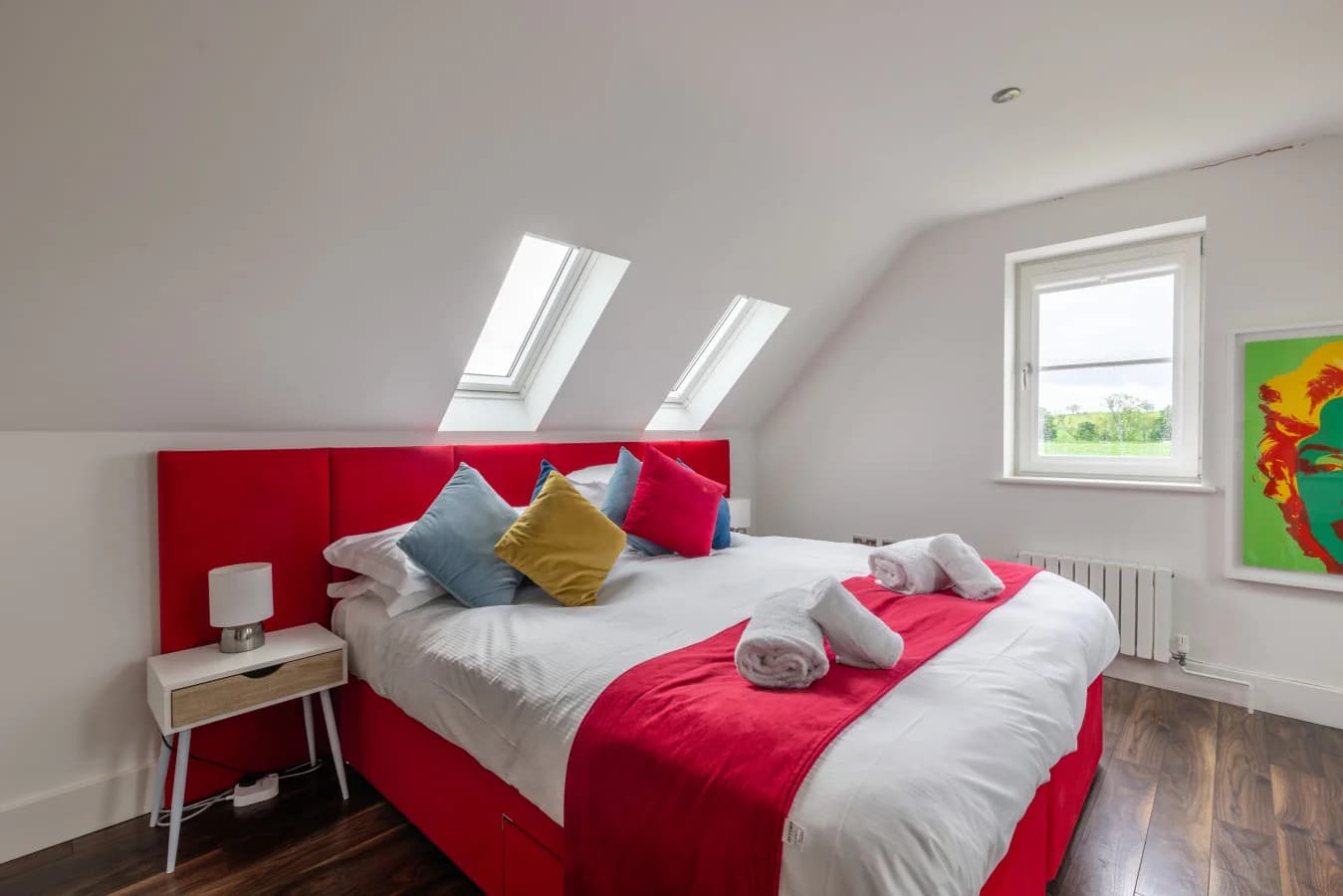 King bedroom with red upholstered headboard and skylights