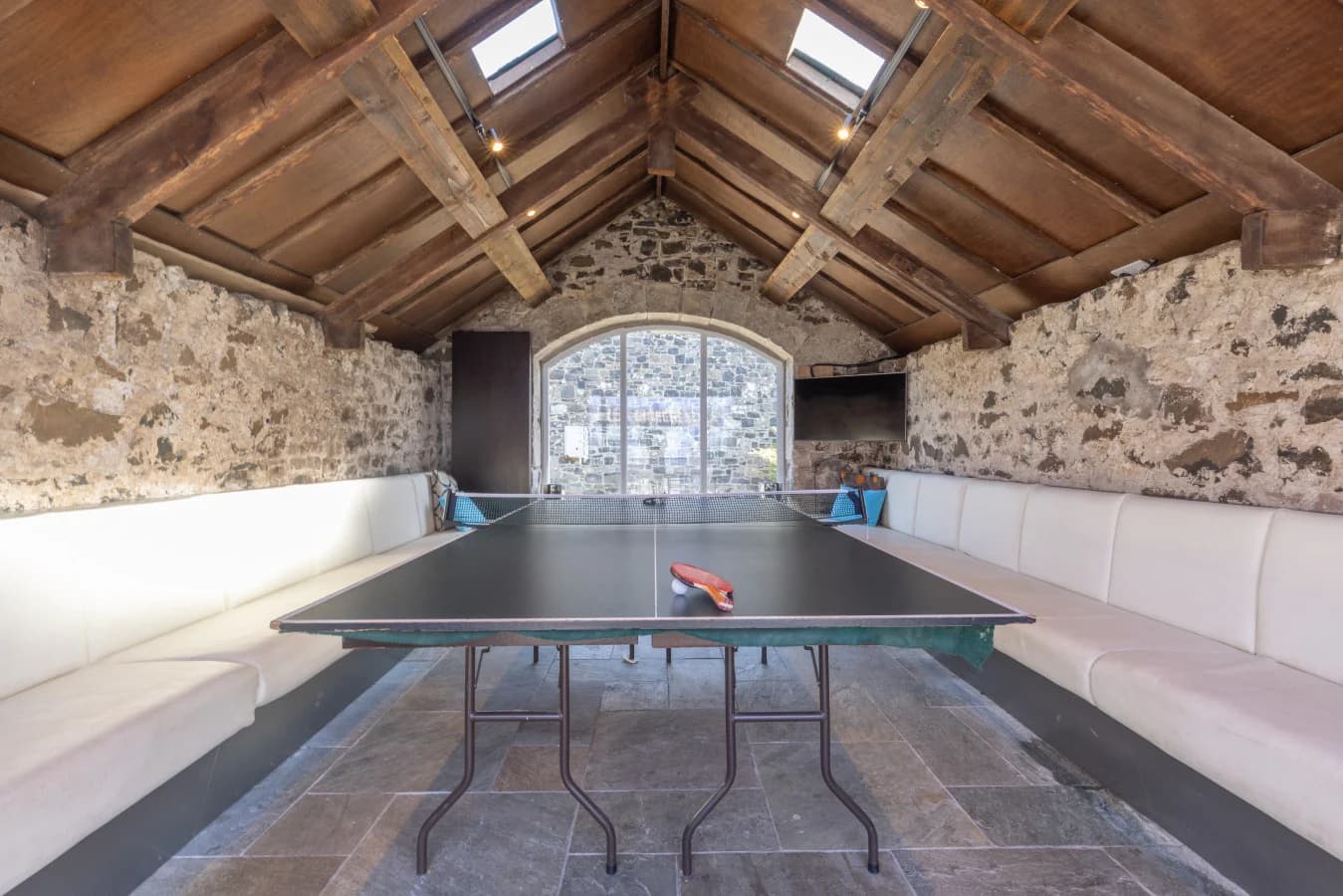 Recreation room with table tennis and exposed stone walls