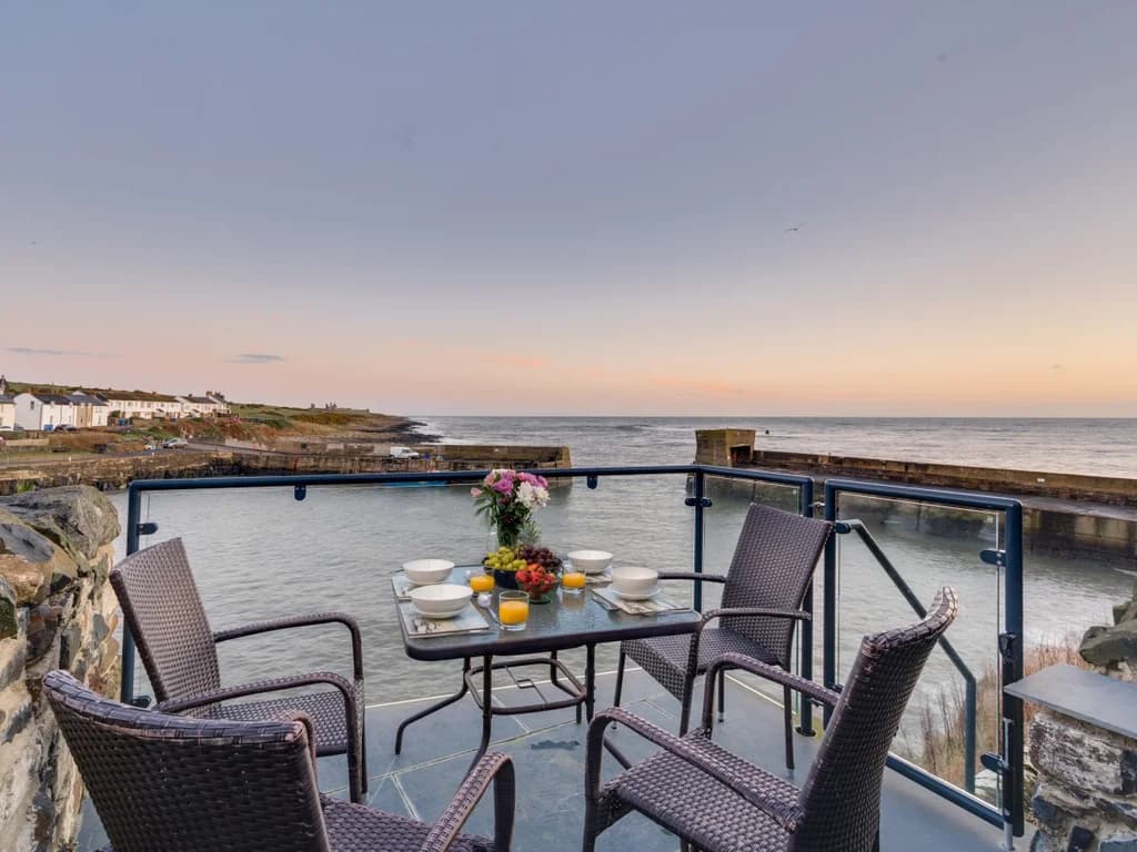Majestic private balcony overlooking Craster Harbour, with outdoor seating for enjoying the spectacular coastal views.