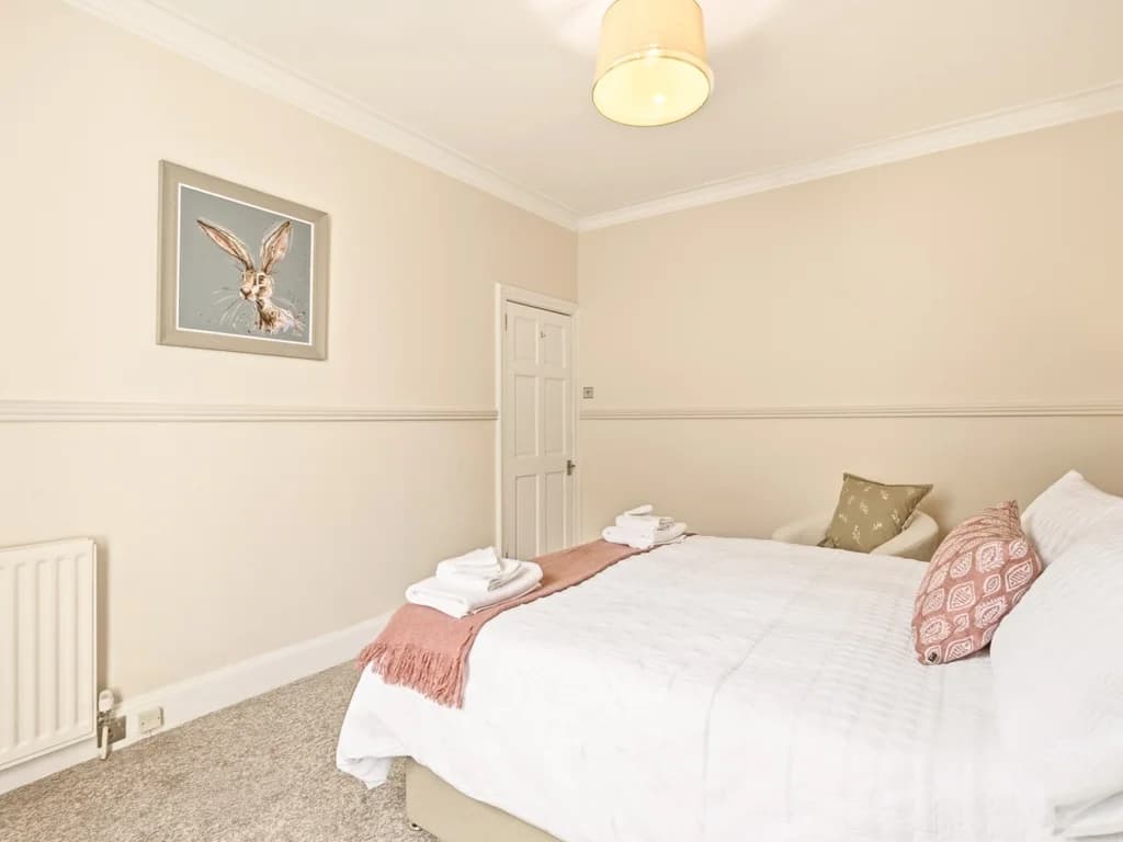 King bedroom with framed artwork and upholstered headboard.
