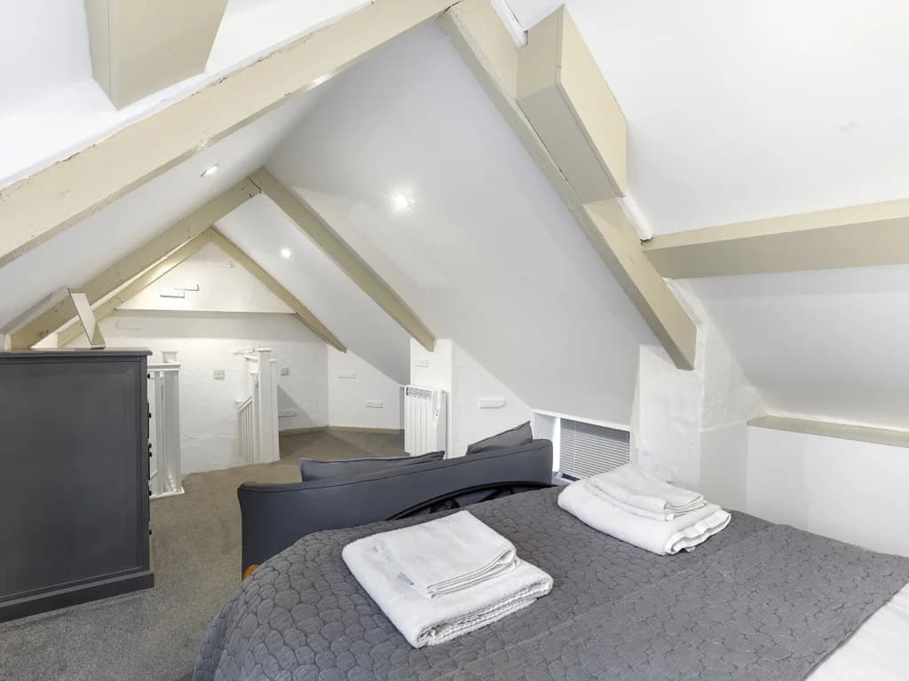 Vaulted bedroom with exposed beams, skylight and soft grey furnishings