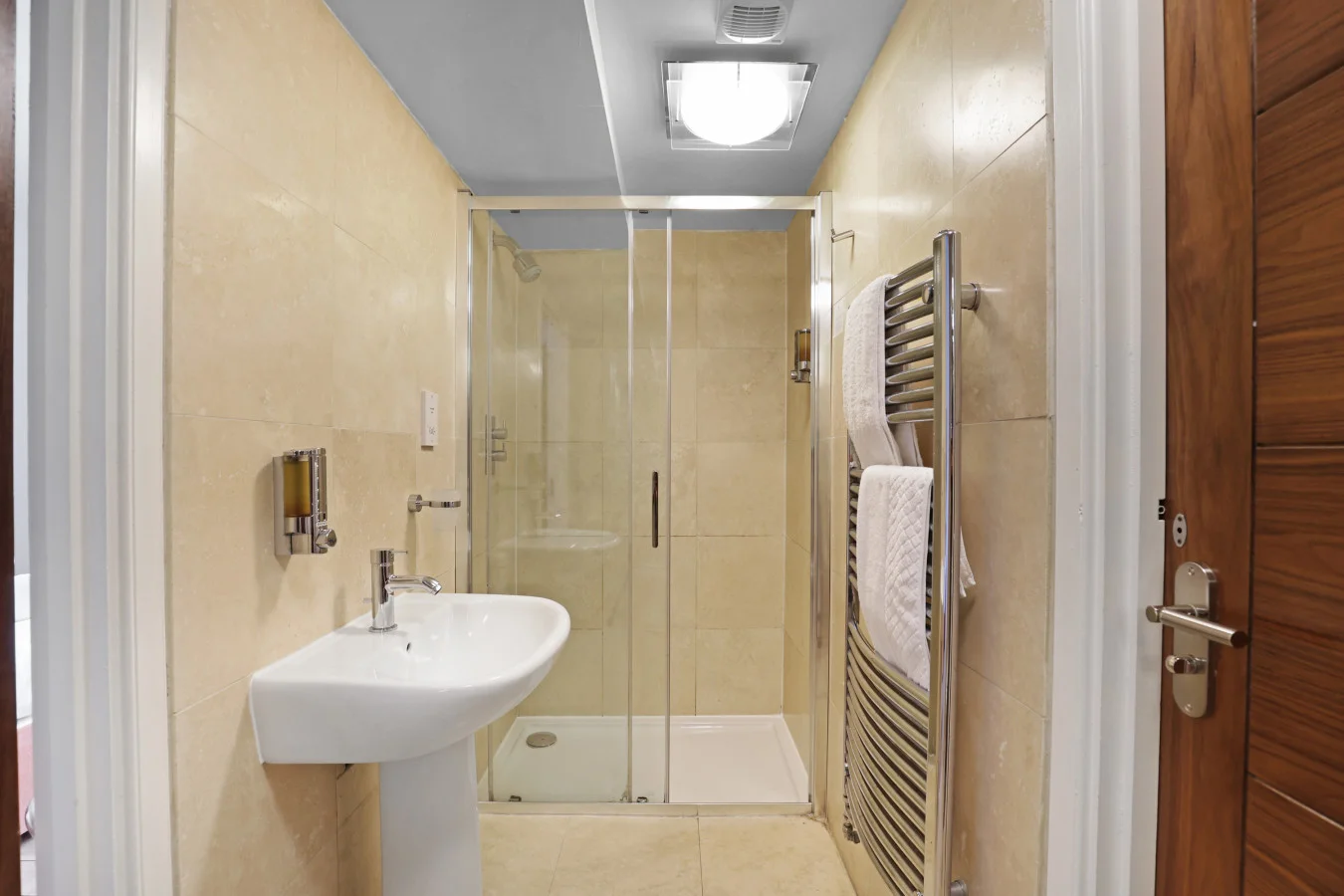 Walk-in shower room with heated towel rail and stone tiles