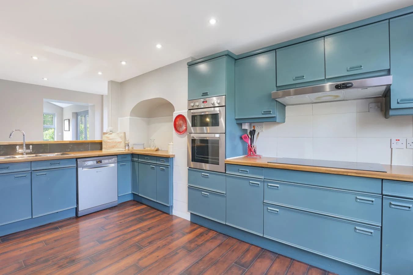 Well-equipped kitchen with blue units, timber counters and ample space