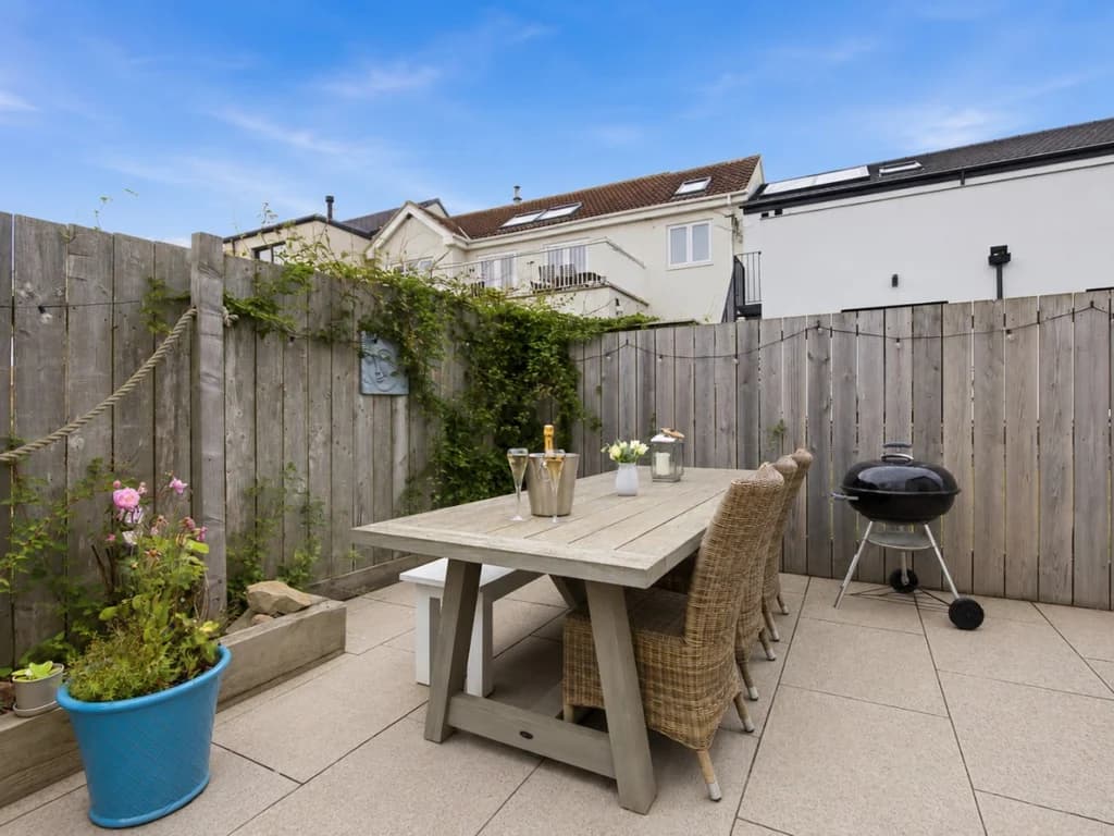 Patio with outdoor dining table, charcoal BBQ and enclosed fencing