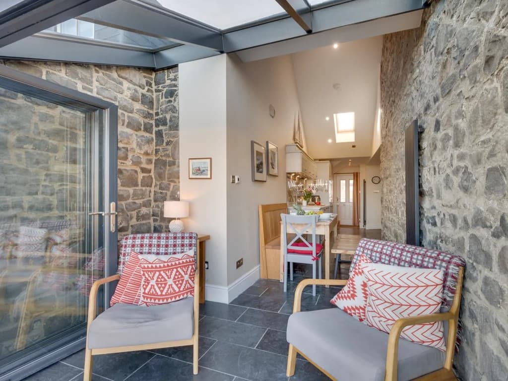 Characterful seating area with exposed stone walls and a light-filled glass roof.