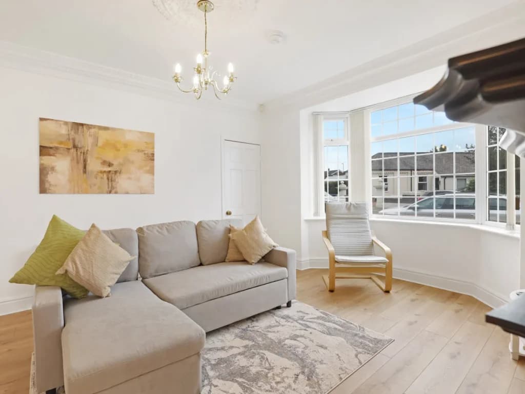Comfortable corner sofa and armchair beside the bright bay window