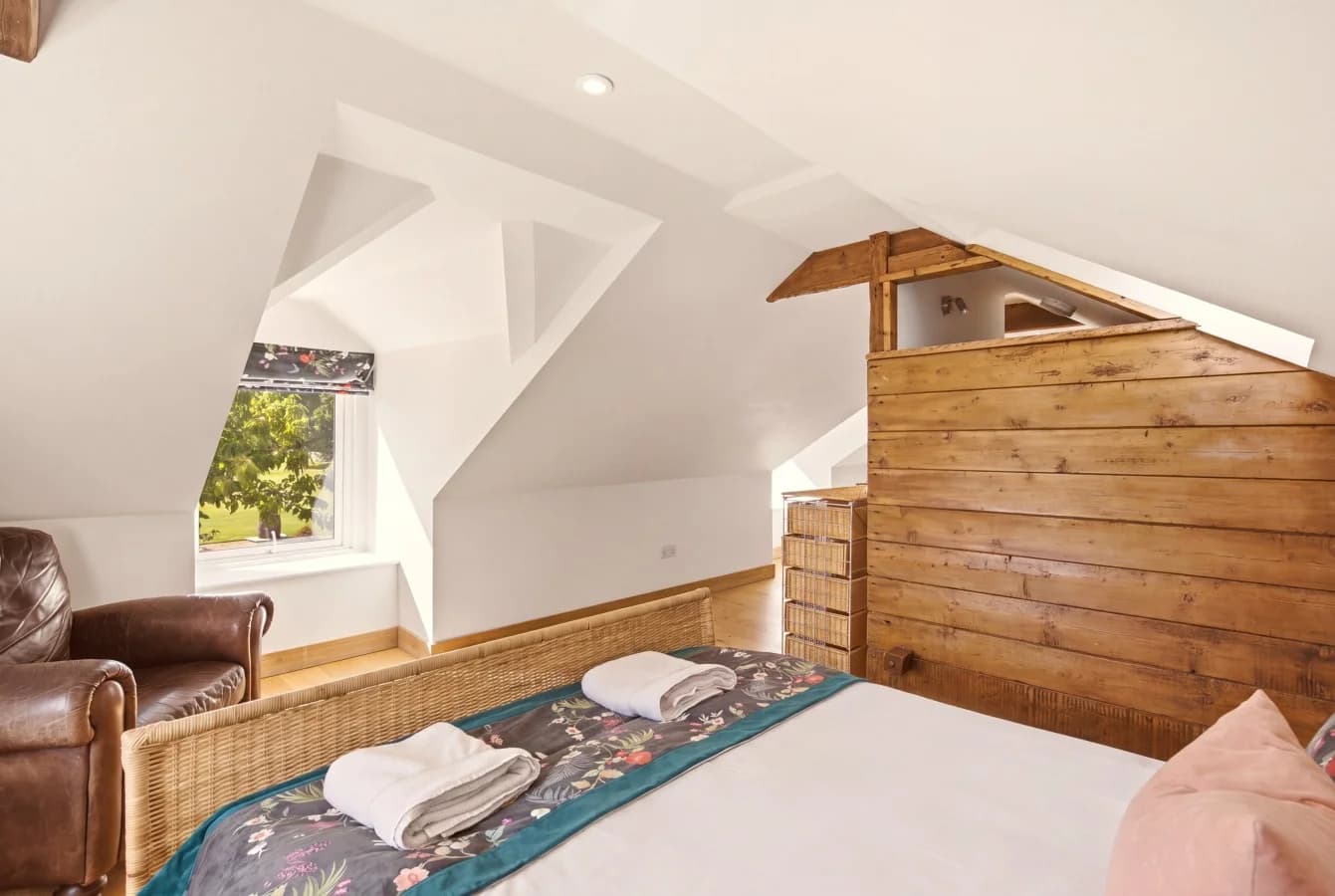 Hayloft bedroom framed by sloping ceilings and exposed timber beams