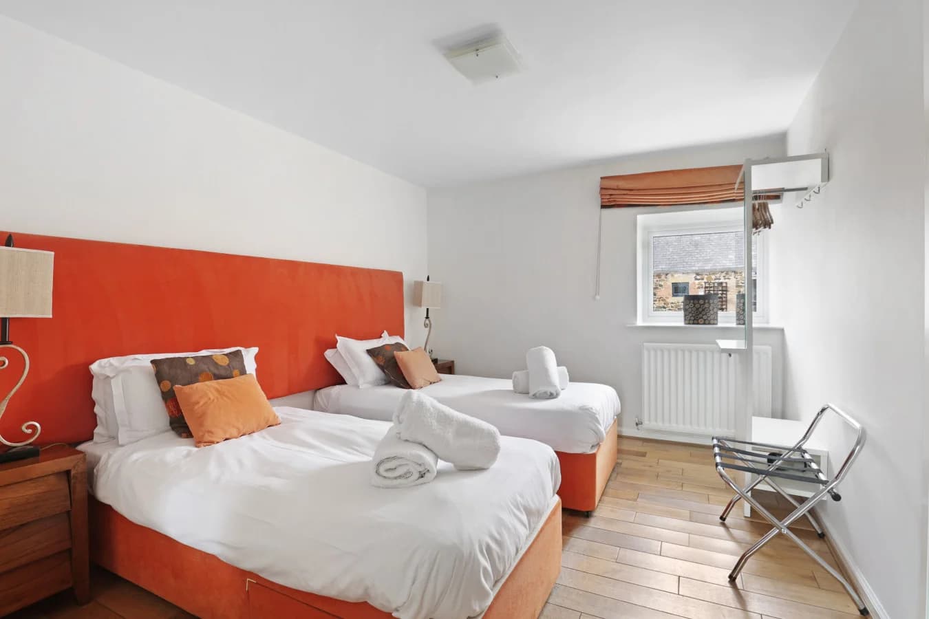 Twin bedroom with orange headboards and bedside tables