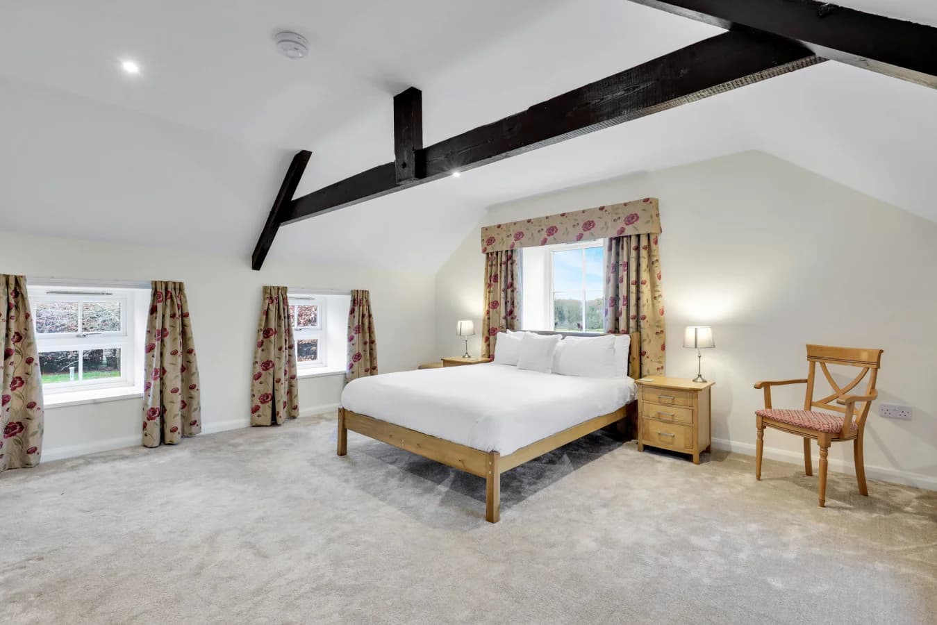 Characterful bedroom with floral drapes and exposed roof timbers