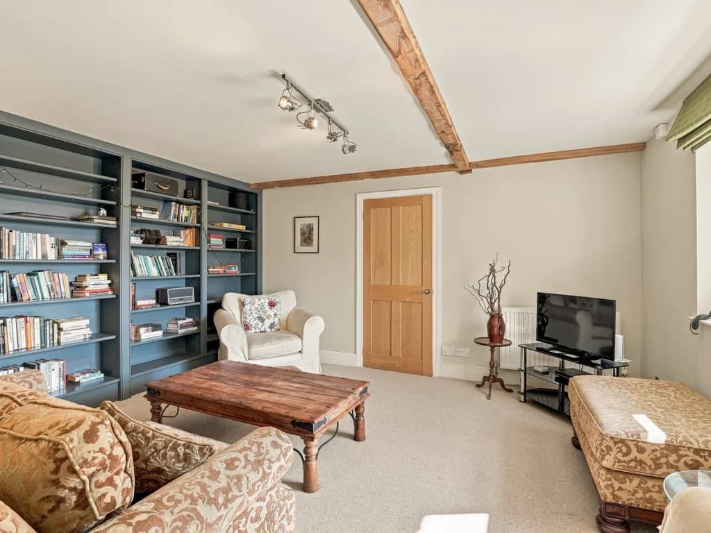 Living room with bookshelves, TV and exposed timber beams