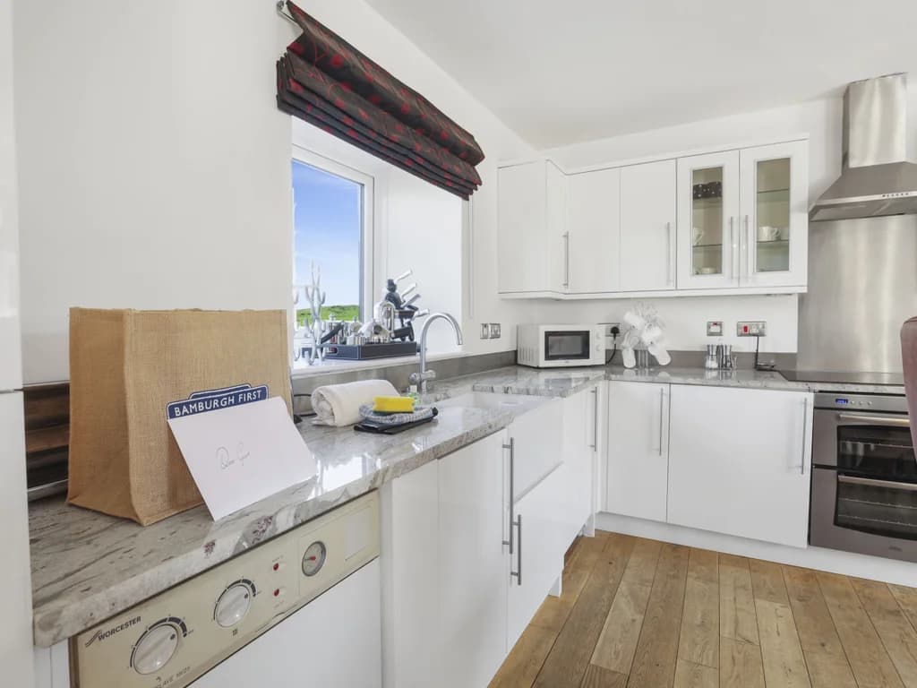 White fitted kitchen with integrated appliances and oak worktops.