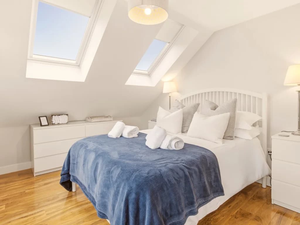 First-floor king bedroom with skylights, oak flooring and blue throw blanket