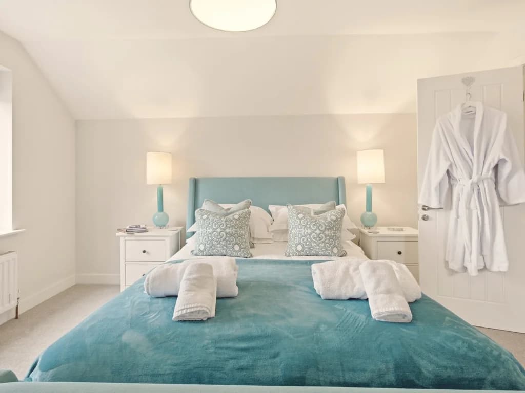 First floor king bedroom with teal upholstered bed and en-suite bathroom