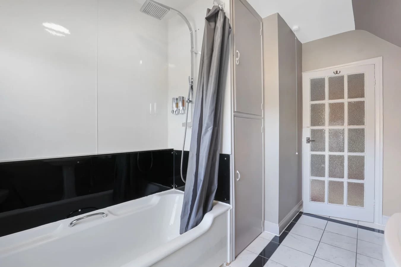 Family bathroom with bath, shower screen and neutral tiled walls