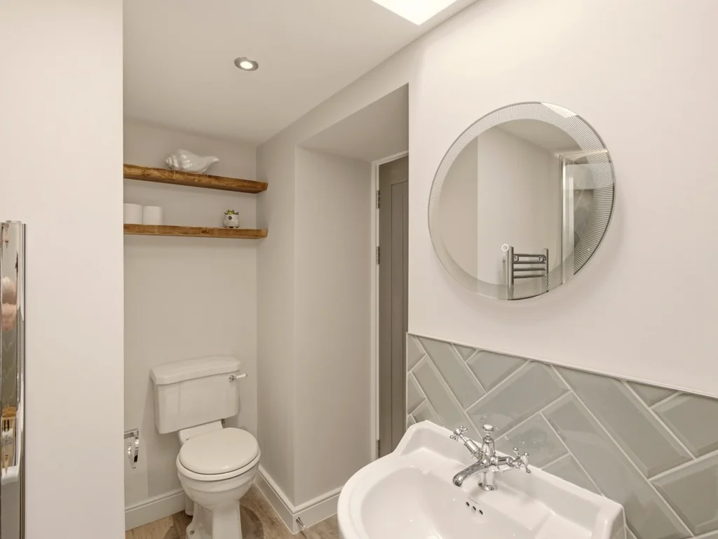 Bright family bathroom with heated towel rail, floating shelves and WC