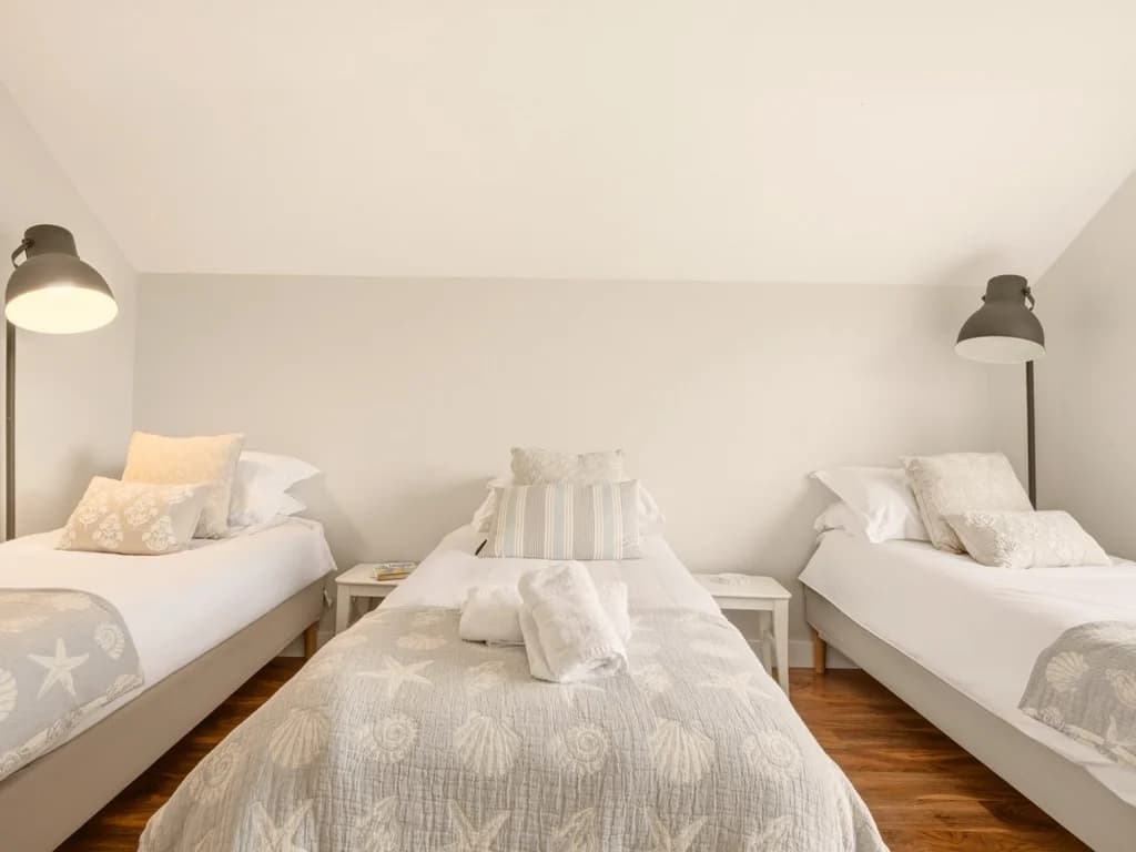 Family bedroom with three single beds, bedside tables and oak flooring