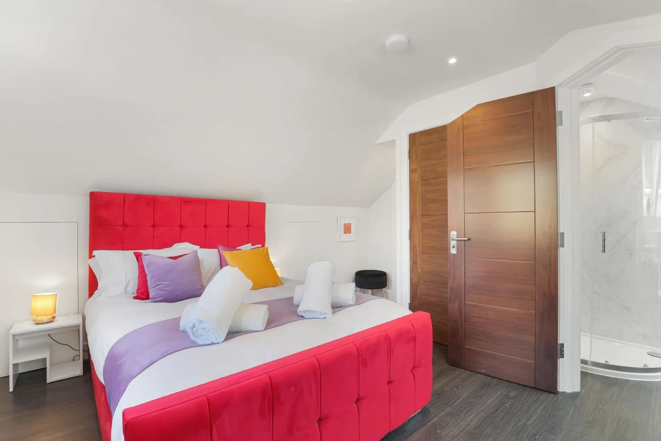 King bedroom with red upholstered headboard and en-suite access